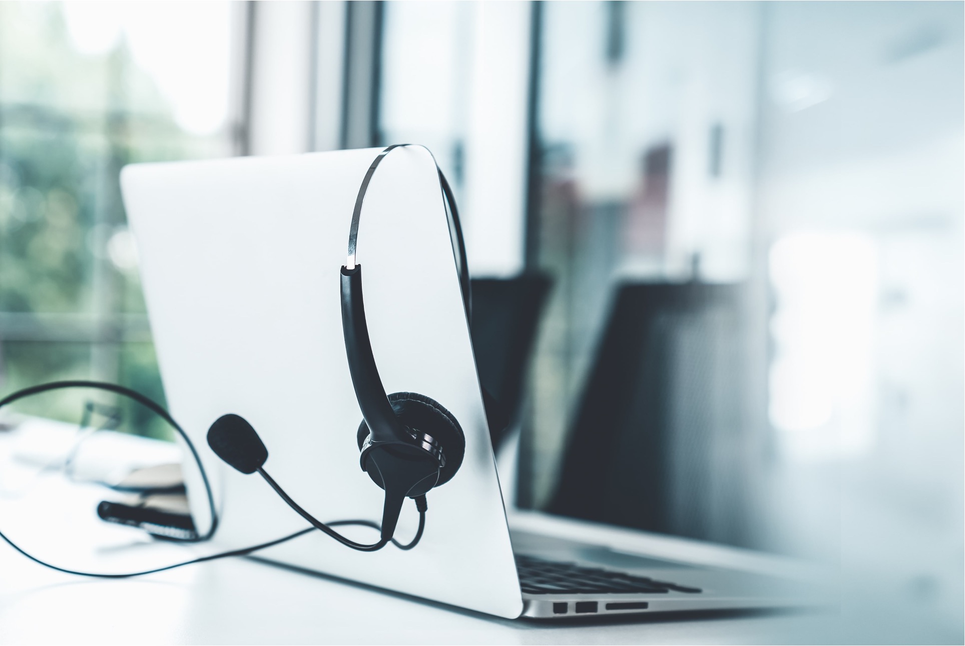 A laptop computer with a headset on top of it.