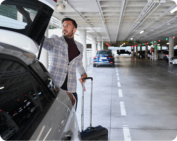 A man with a suitcase is standing next to a car.