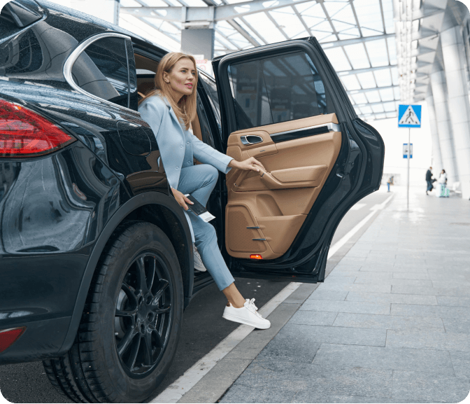 A woman sitting on the door of a car.