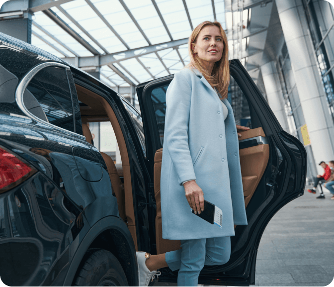 A woman in a blue coat is getting out of a car.